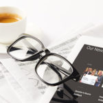 eyeglasses, coffee cup, digital tablet and pile of newspapers, o